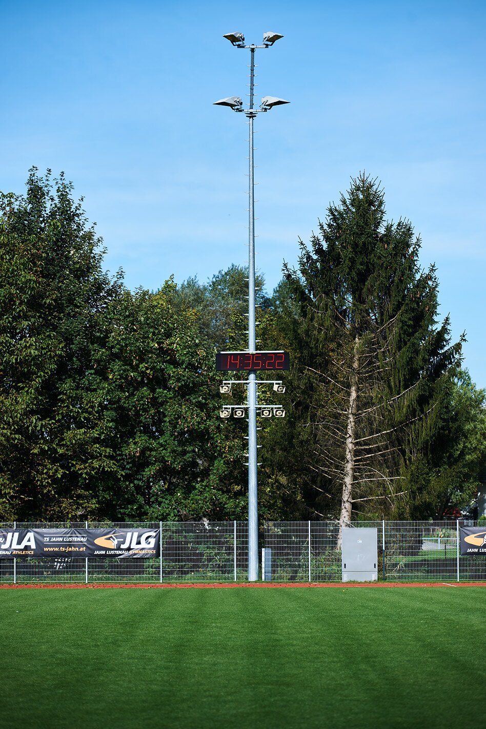 Athletics track with floodlight column on which a 6-digit LED display board is mounted